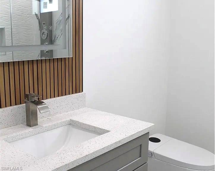 Modern bathroom vanity featuring a light grey cabinet, speckled countertop with integrated sink, and a contemporary brushed nickel faucet