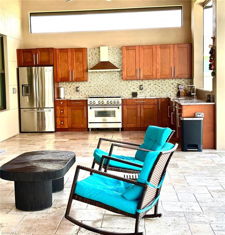 Kitchen with stone tile floors, stainless steel appliances, wood finish cabinets, light stone counters, and tasteful backsplash