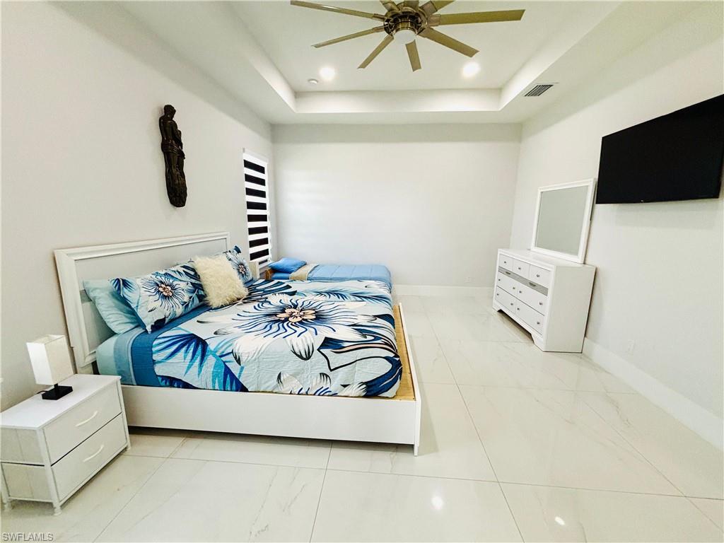 Bedroom with ceiling fan, a raised ceiling, and recessed lighting