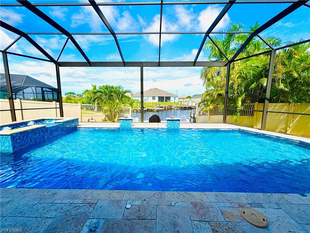 Relaxing pool / spa with a sunroom, a fenced backyard, a lanai, and a water view
