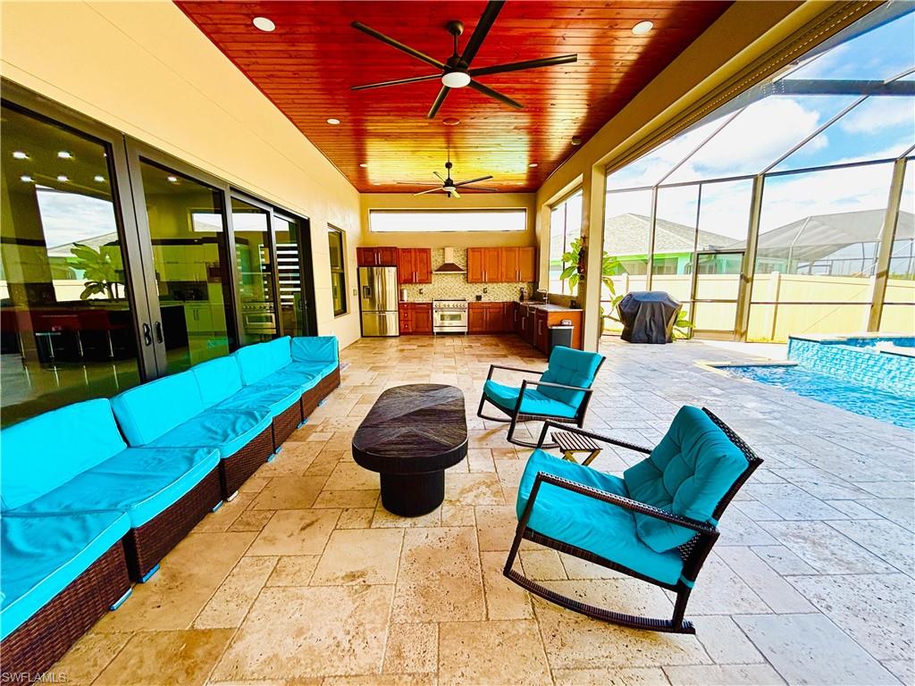 View of patio / terrace with an outdoor kitchen with living area, ceiling fan, glass enclosure, a sunroom, and an outdoor pool