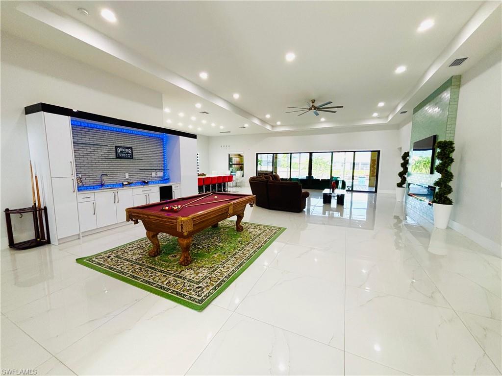Rec room featuring billiards, a ceiling fan, a tray ceiling, recessed lighting, and bar area