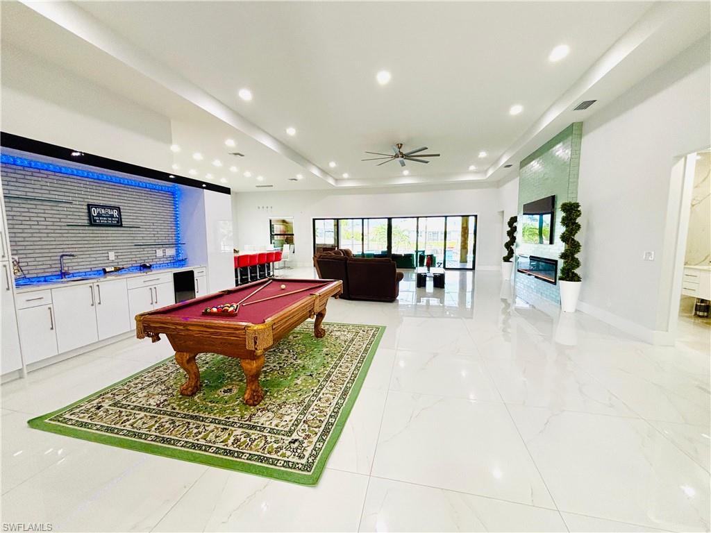 Game room with ceiling fan, billiards table, a raised ceiling, recessed lighting, and bar area