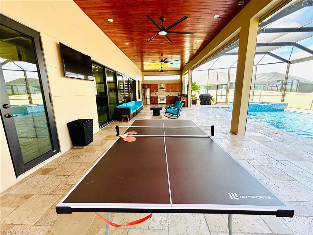 View of patio with an outdoor pool, a ceiling fan, glass enclosure, a sunroom, and an outdoor living / dining area