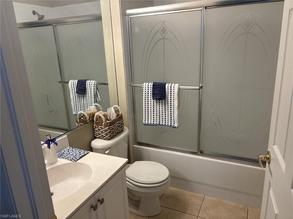 Bathroom featuring vanity, bath / shower combo with glass door, and tile patterned flooring