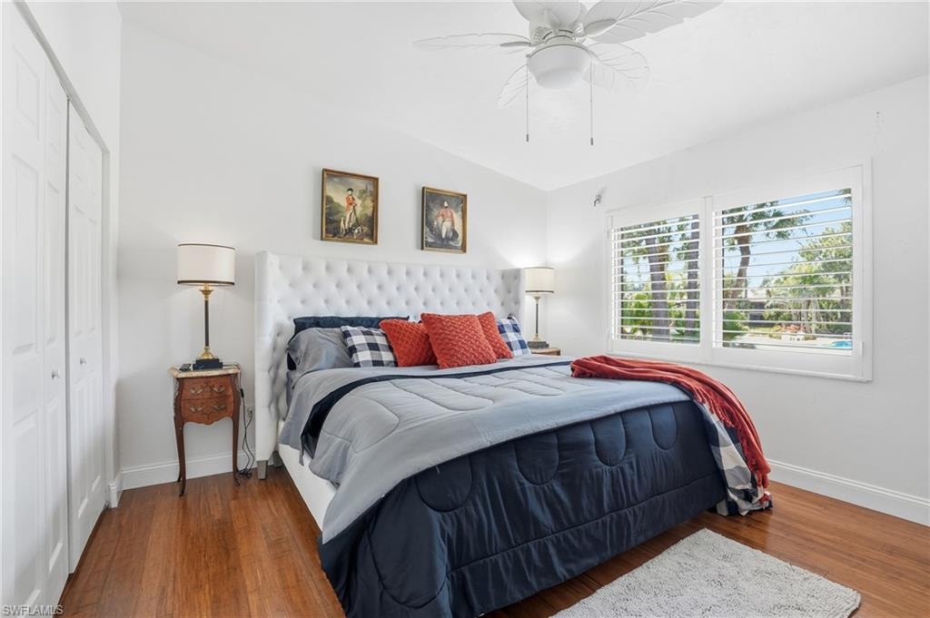 Guest Bedroom with lofted ceiling, plantation shutters, view of pool and bamboo flooring