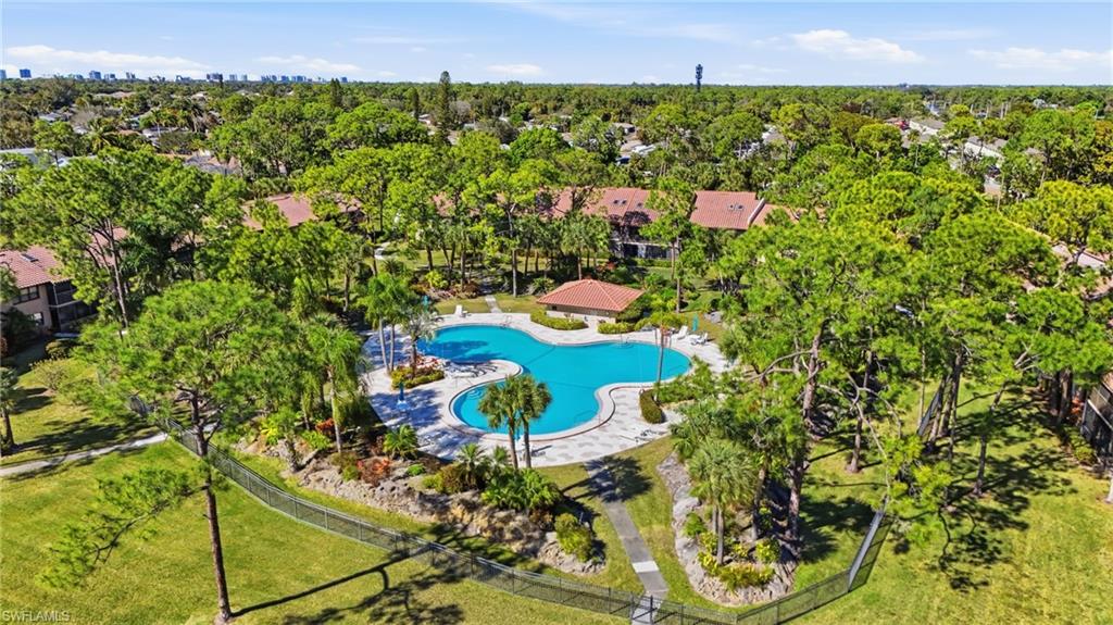 Aerial view of the tree-lined landscape, very large resort style pool, and plenty of green space