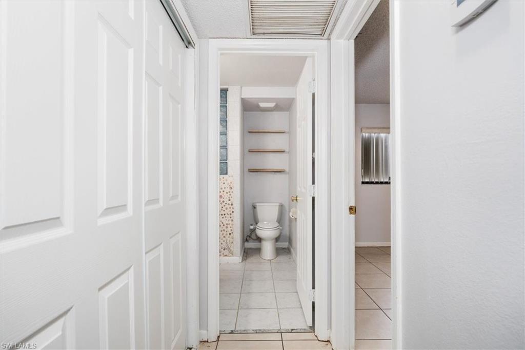 Hall featuring light tile patterned floors and a textured ceiling
