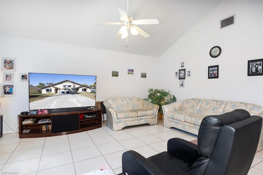 Tiled living area featuring vaulted ceiling and a ceiling fan