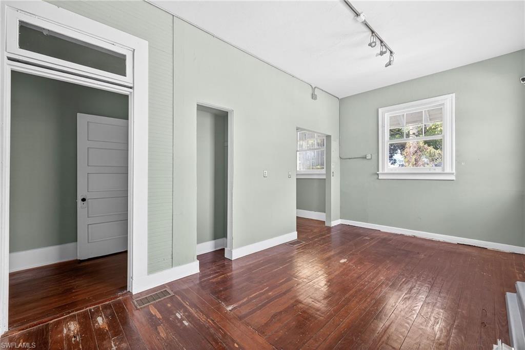 Unfurnished room featuring rail lighting and dark wood-type flooring