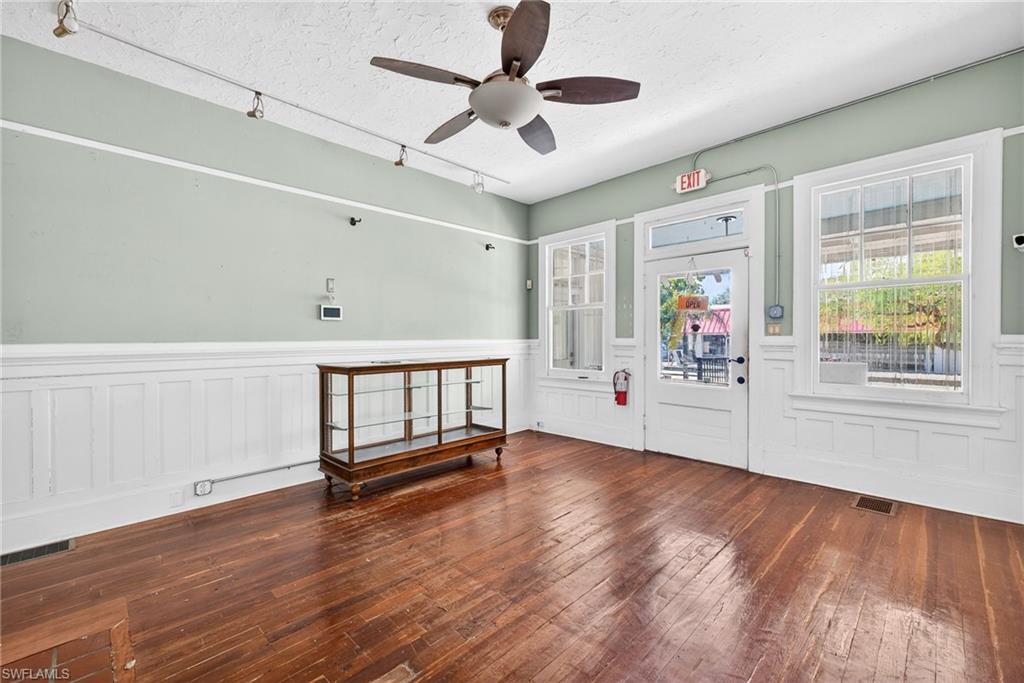 Foyer entrance featuring dark wood-style floors, a wainscoted wall, plenty of natural light, a textured ceiling, and rail lighting