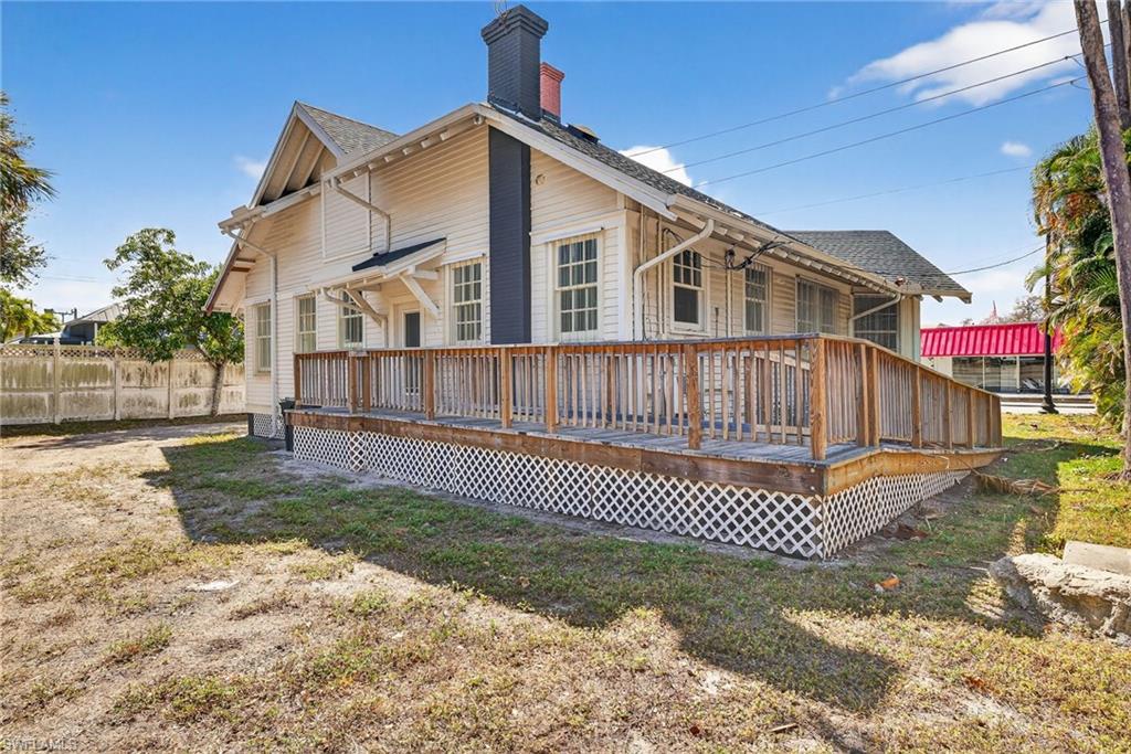Back of property with a deck, a shingled roof, and a chimney