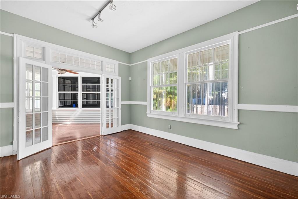 Empty room with dark wood-type flooring, healthy amount of natural light, rail lighting, and a ceiling fan
