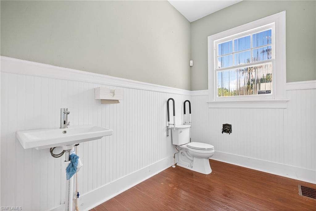 Bathroom with wainscoting and dark wood-type flooring