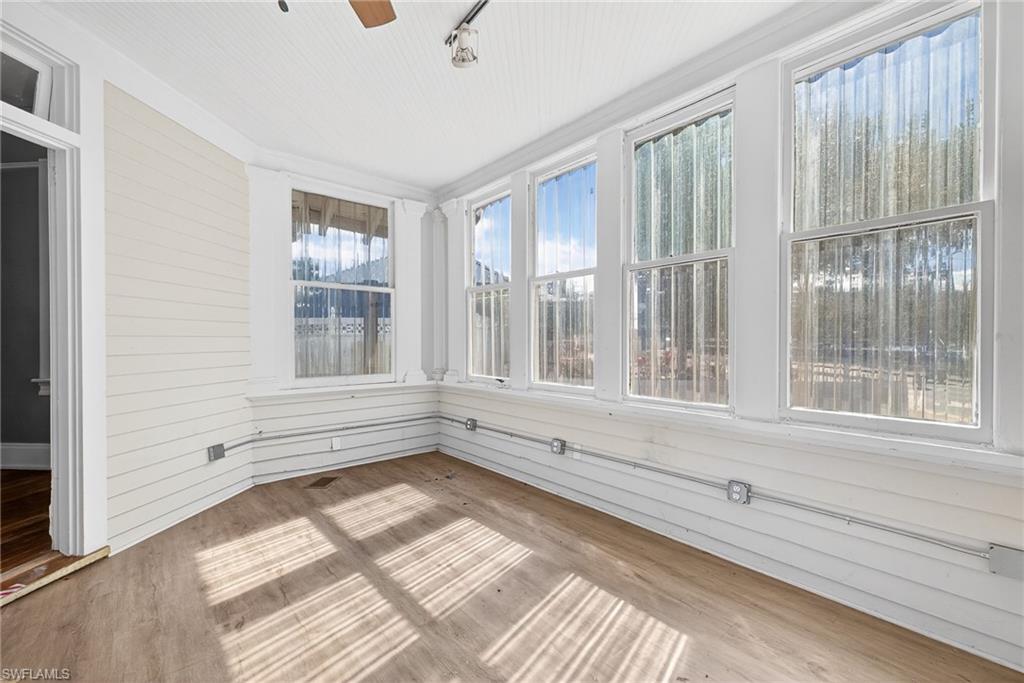 Unfurnished sunroom with wood finished floors and wood walls