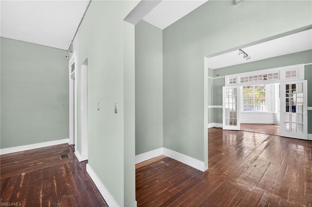 Hall with dark wood-type flooring, french doors, and a high ceiling