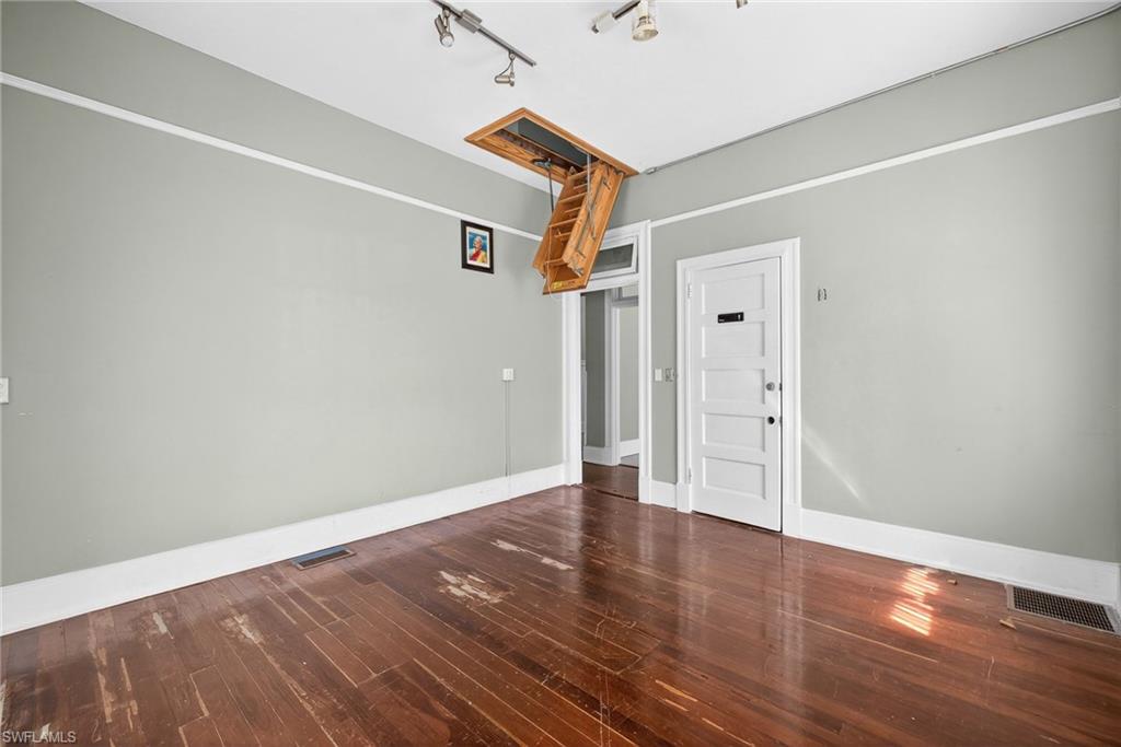 Empty room featuring dark wood-style flooring and track lighting