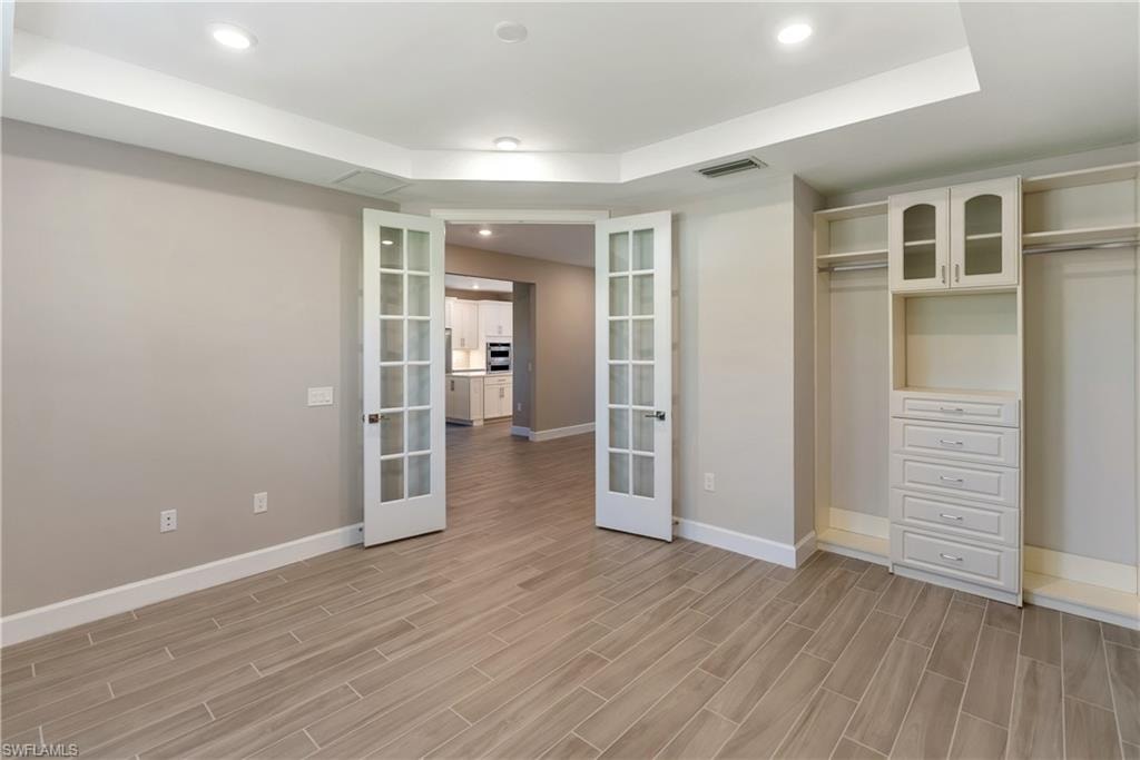 Bedroom/ Flex area with a raised ceiling, recessed lighting, french doors, wood tiled floors, and a closet
