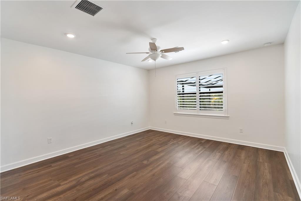 Primary bedroom with dark wood-style LVP floors, a ceiling fan, and recessed lighting