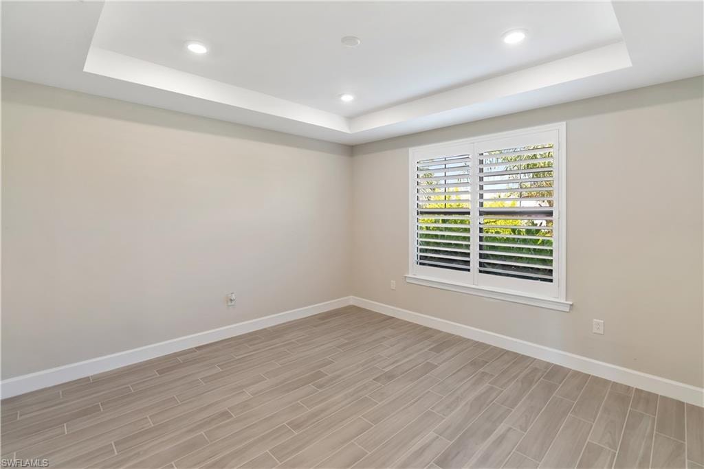 Bedroom/ Flex area with a raised ceiling, recessed lighting, french doors, wood tiled floors, and a closet