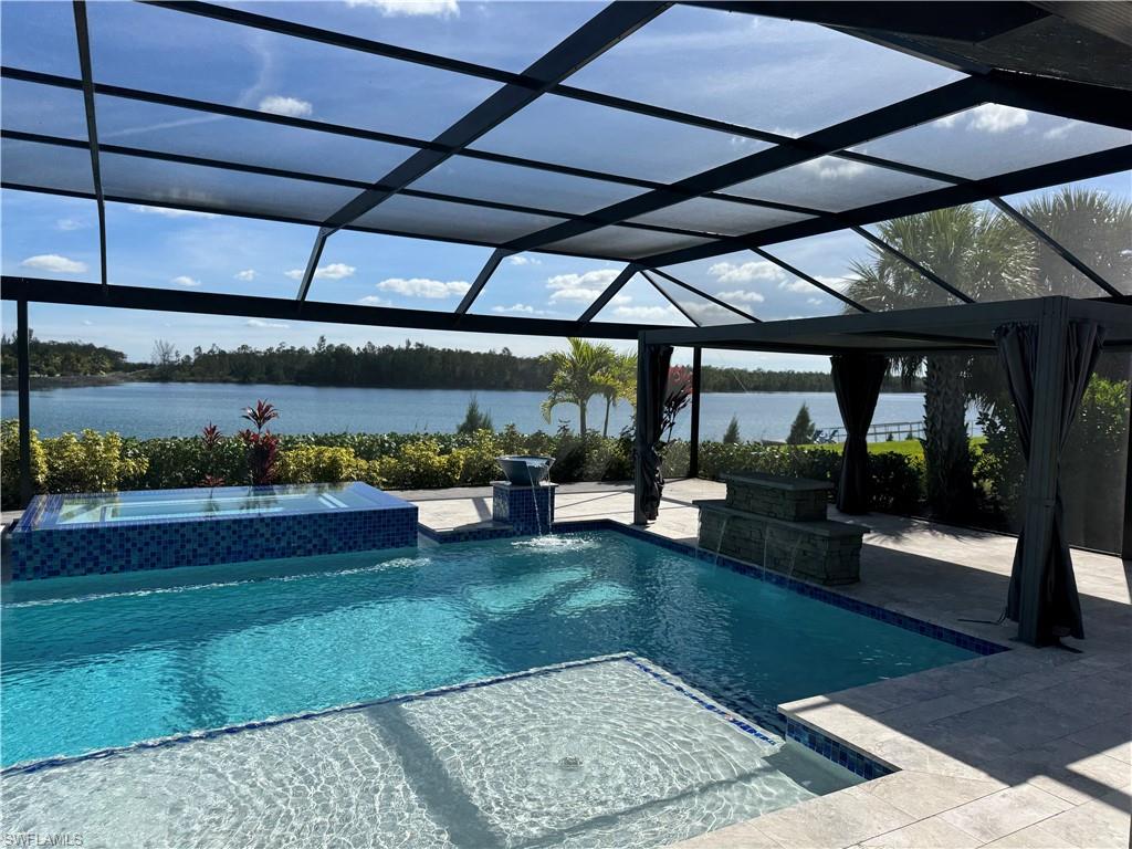 Integrated pool / spa featuring a screen enclosure and a lake view
