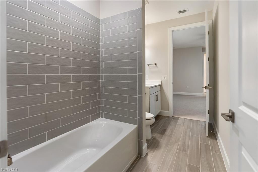 Ensuite bathroom with vanity, shower / bath combination, wood finish floors, and a walk in closet