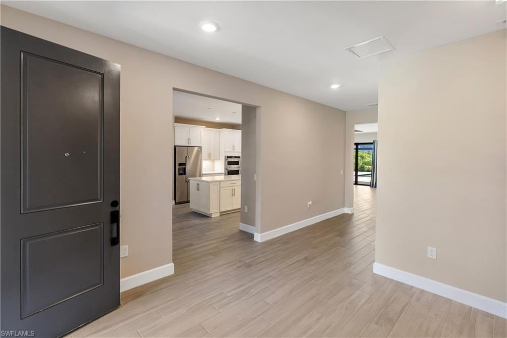 Entrance foyer with light wood-style tile floors and recessed lighting