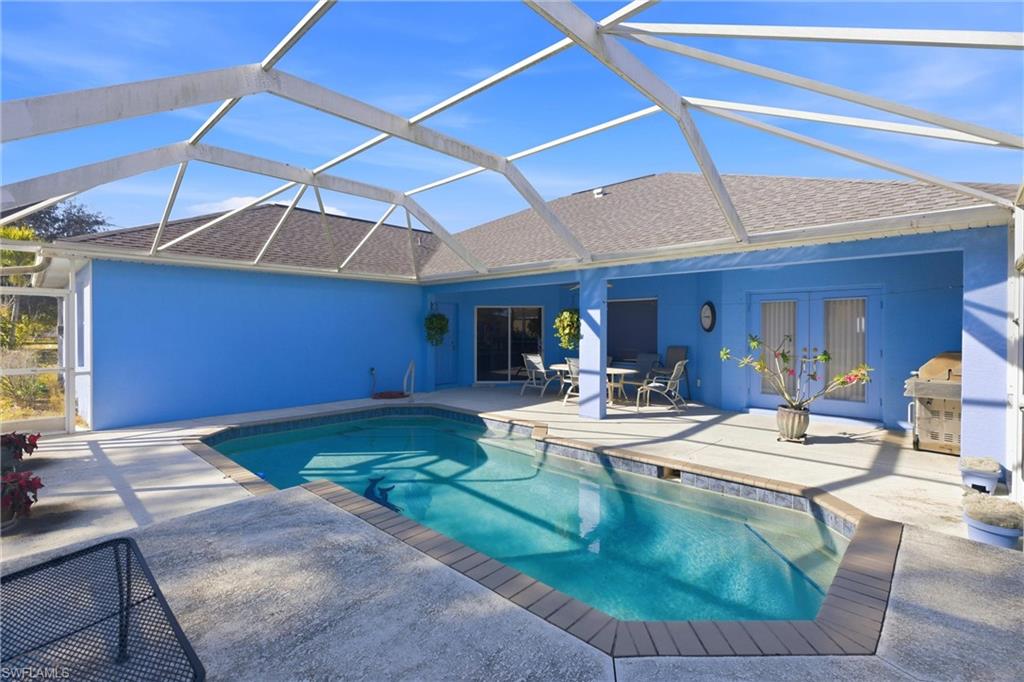 Outdoor pool with a lanai, outdoor dining space, a patio, a sunroom, and french doors