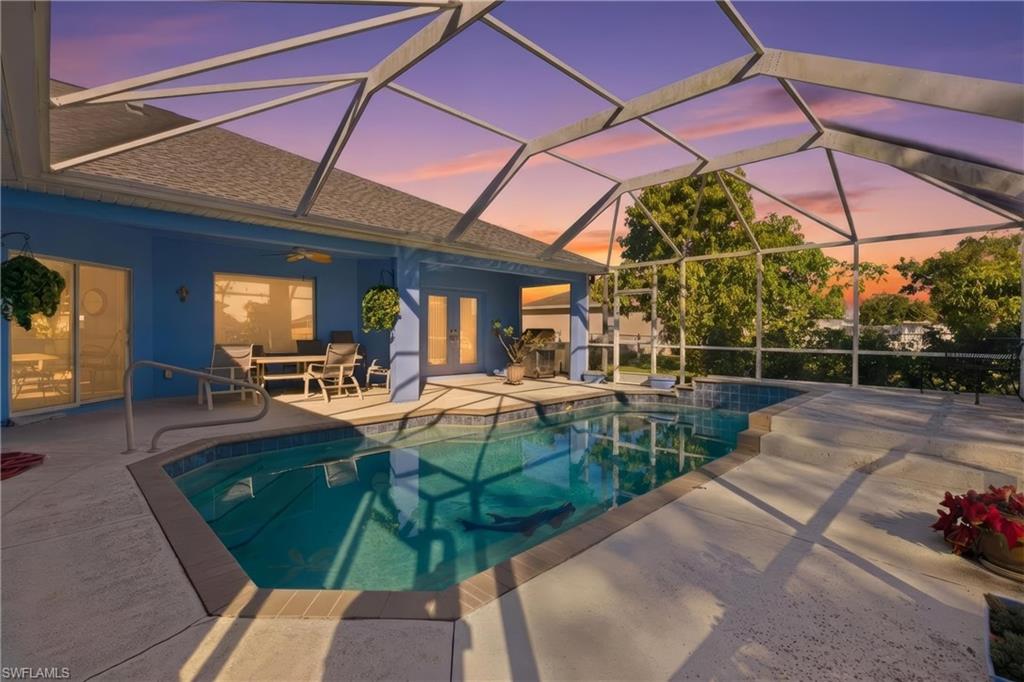 Swimming pool featuring glass enclosure, a patio area, a sunroom, and french doors