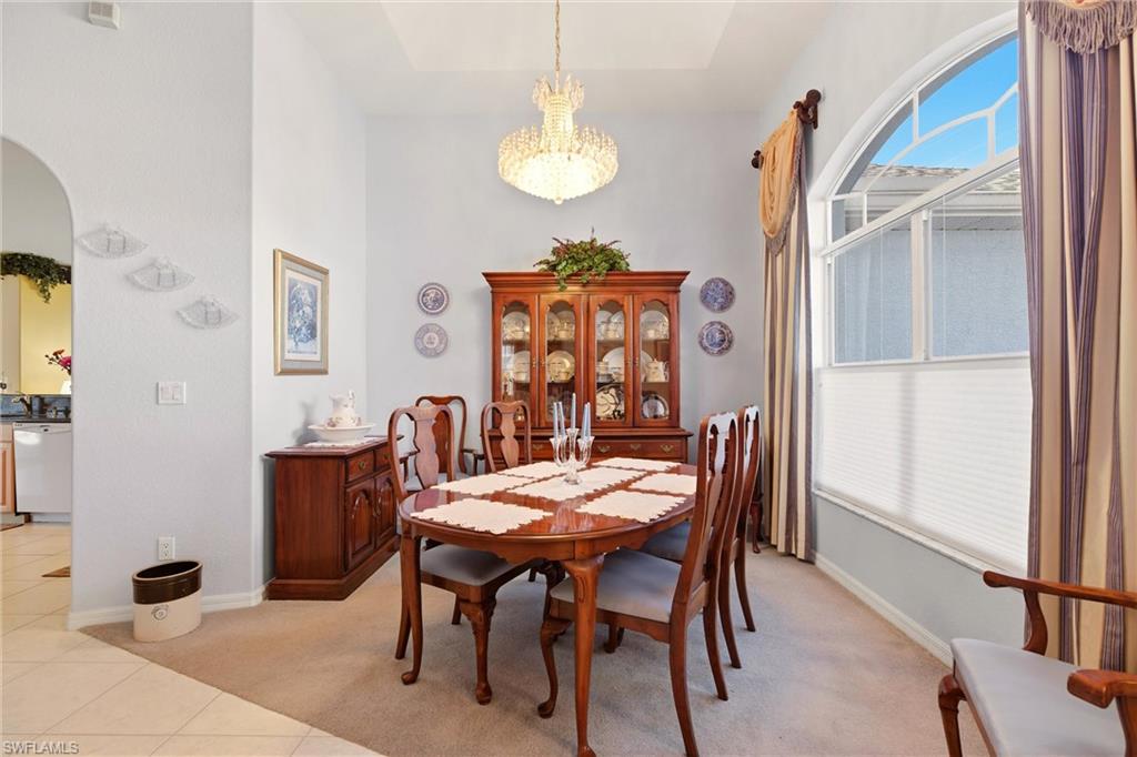 Dining room with suspended lighting, arched walkways, light tile patterned floors, and light carpet