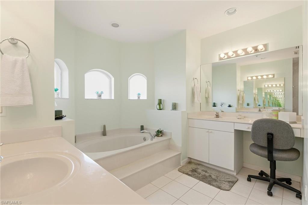 Full bathroom with two vanities, a bath, and light tile patterned flooring