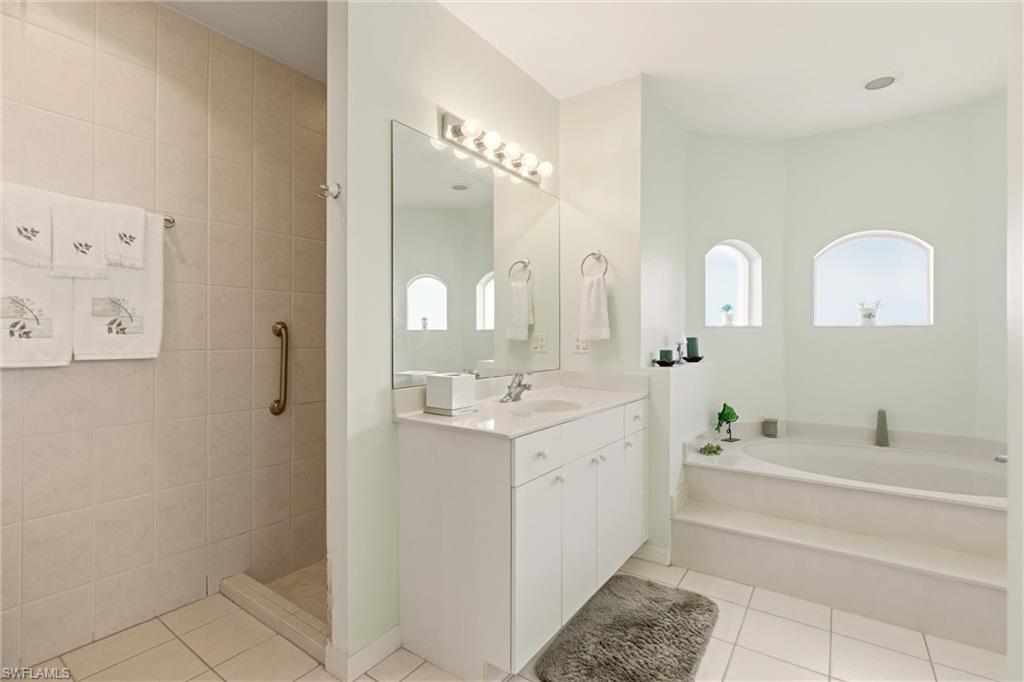 Full bathroom with vanity, light tile patterned floors, a bath, and a walk in shower