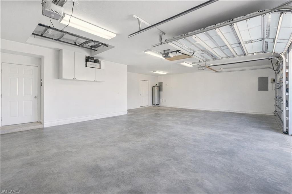 Garage featuring a garage door opener, water heater, and electric panel
