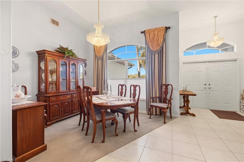 Dining room featuring a chandelier, a high ceiling, light colored carpet, and light tile patterned flooring