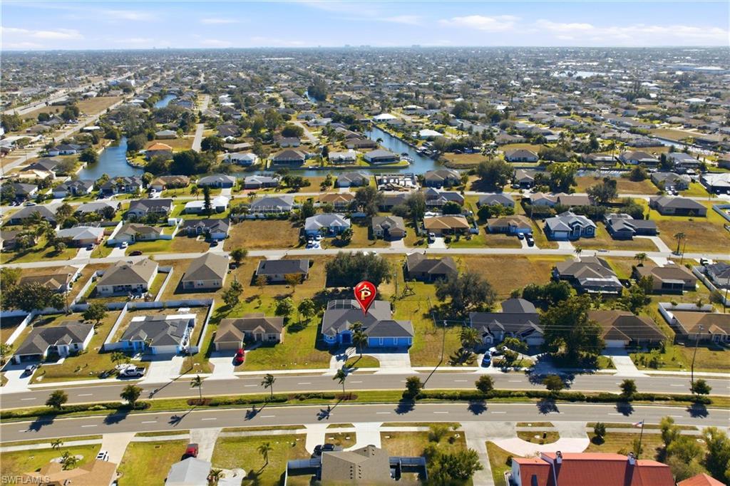 Aerial view of property and surrounding area featuring nearby suburban area and a large body of water