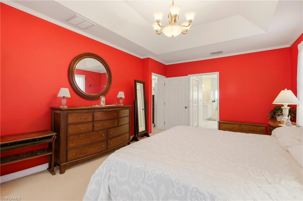 Bedroom with hanging lights, crown molding, and light colored carpet