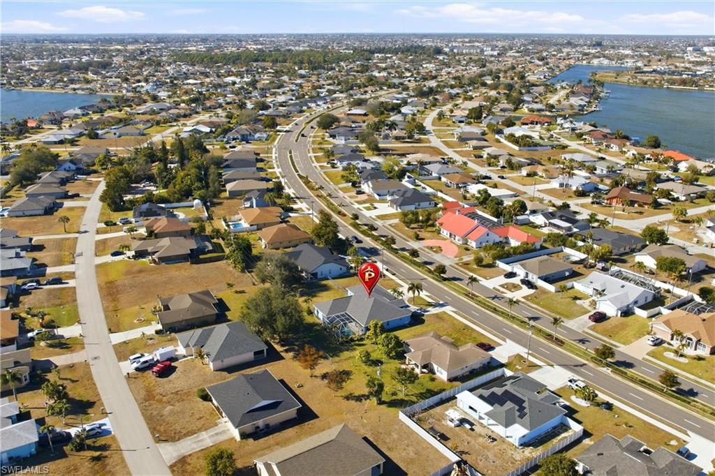 Aerial view of property and surrounding area featuring nearby suburban area and a large body of water