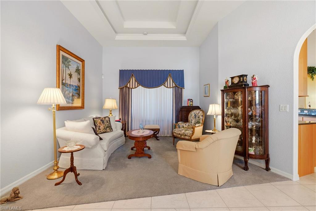Sitting room with arched walkways, a raised ceiling, carpet flooring, and tile patterned flooring