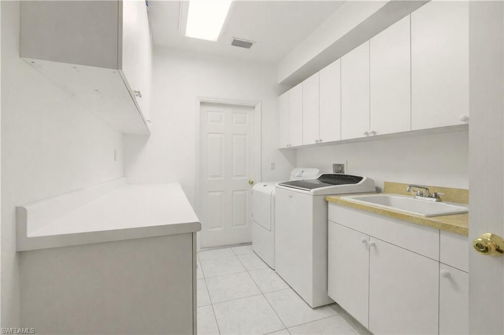 Laundry area featuring cabinet space, light tile patterned floors, and washing machine and dryer