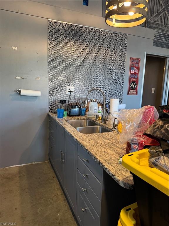 Kitchen with gray cabinets, a breakfast bar area, light stone countertops, and eat-in counter.