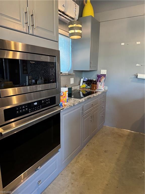 Kitchen featuring stainless steel oven, light stone counters, black electric stovetop, and gray cabinetry