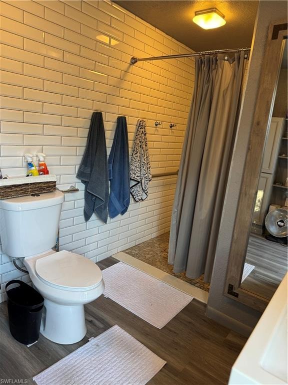 Full bathroom featuring tiled shower, dark wood-type flooring, and a textured ceiling