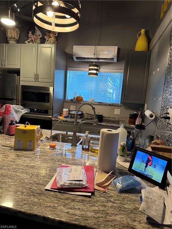 Kitchen featuring oven, pendant lighting, light stone counters, refrigerator, and gray cabinets