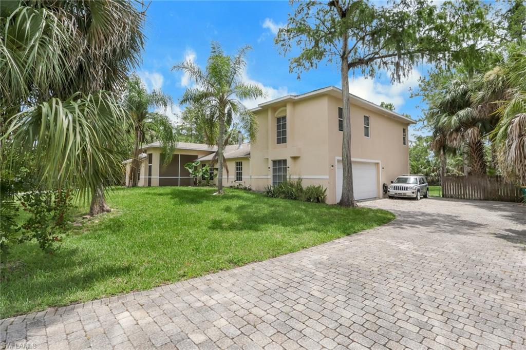 Two-story stucco residence with an attached garage, paver driveway, and a screened lanai