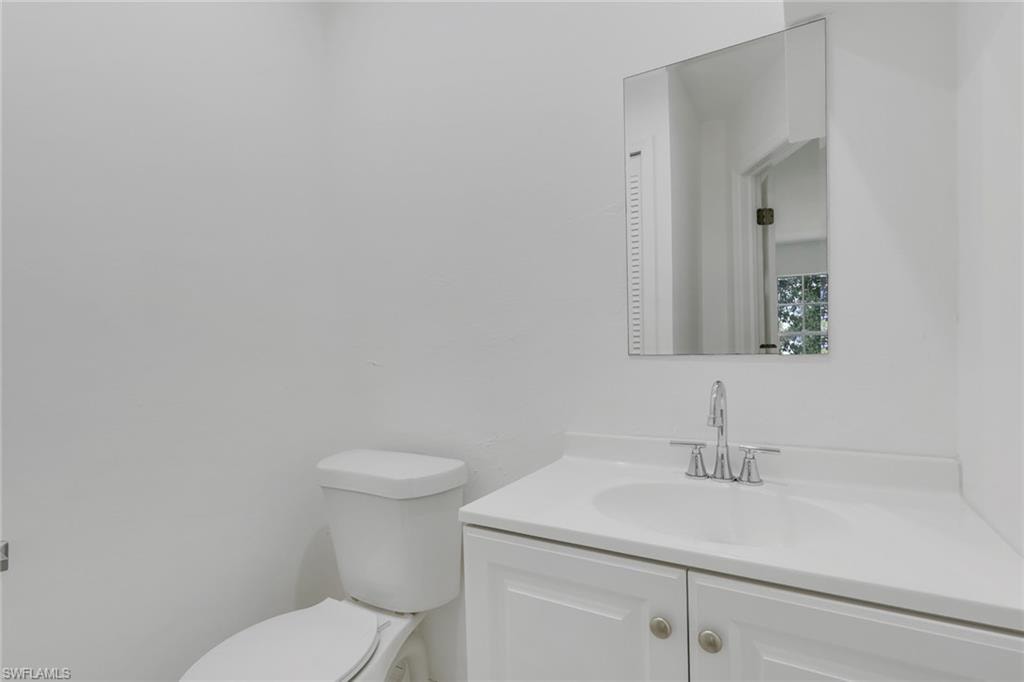 Bathroom featuring a single vanity with a white countertop and integrated sink, chrome-finish faucet, and a rectangular wall-mounted mirror