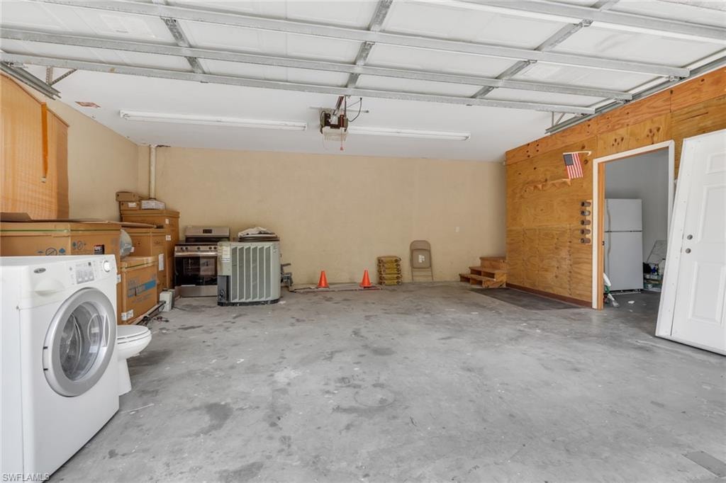 Spacious garage with exposed beam ceiling, concrete flooring, and a dedicated utility area