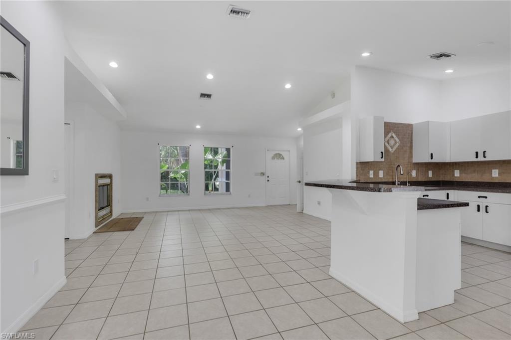 Spacious room featuring neutral-toned tile flooring, recessed lighting, a built-in fireplace, and expansive windows