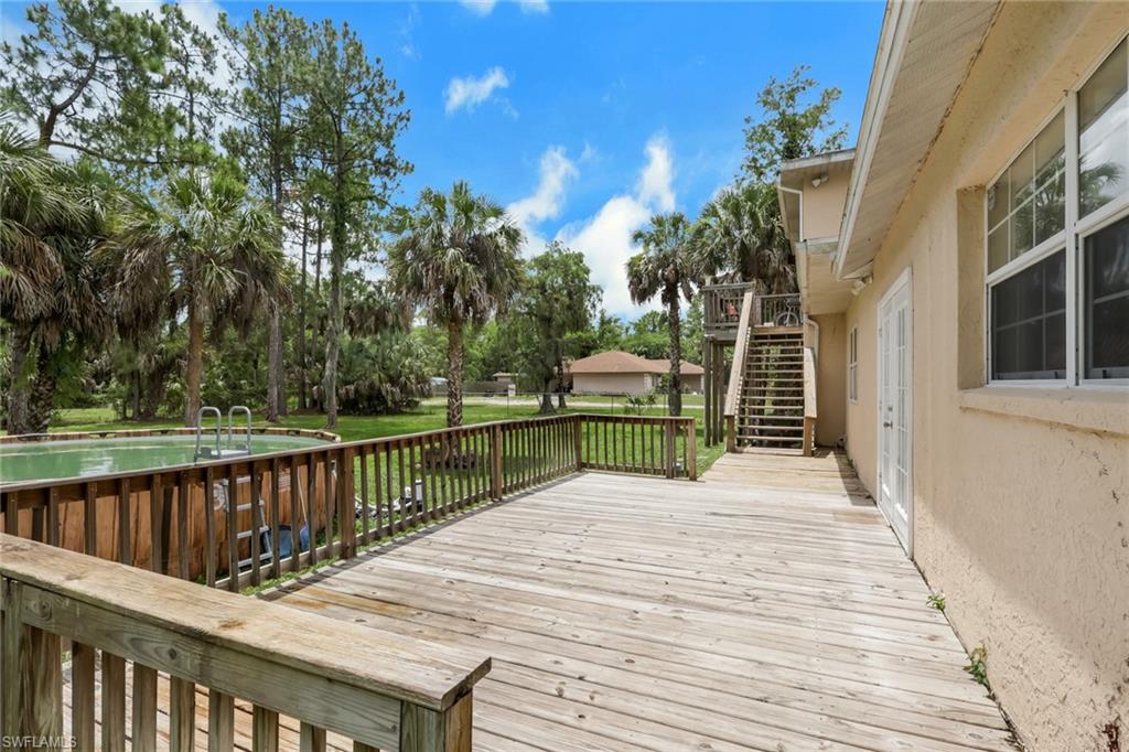 Expansive wood deck with railing and an above-ground pool featuring a ladder