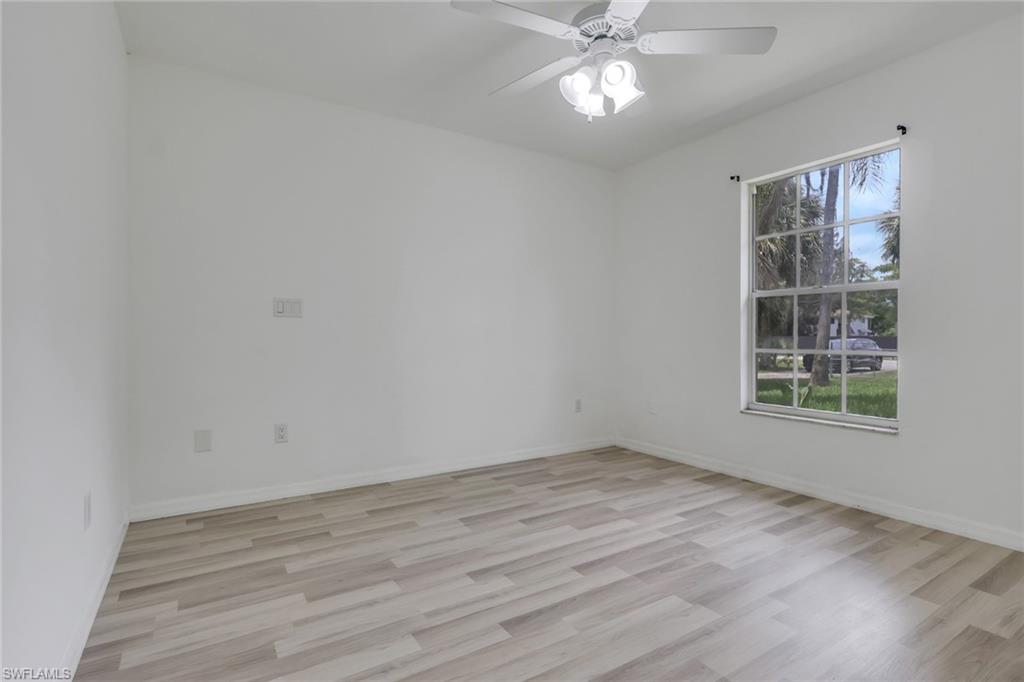 Room featuring wood-finish flooring, white walls, and a multi-pane window with a white frame