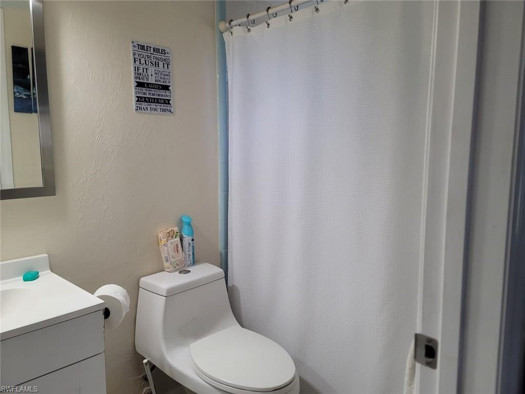 Full bath featuring a textured wall, vanity, and curtained shower